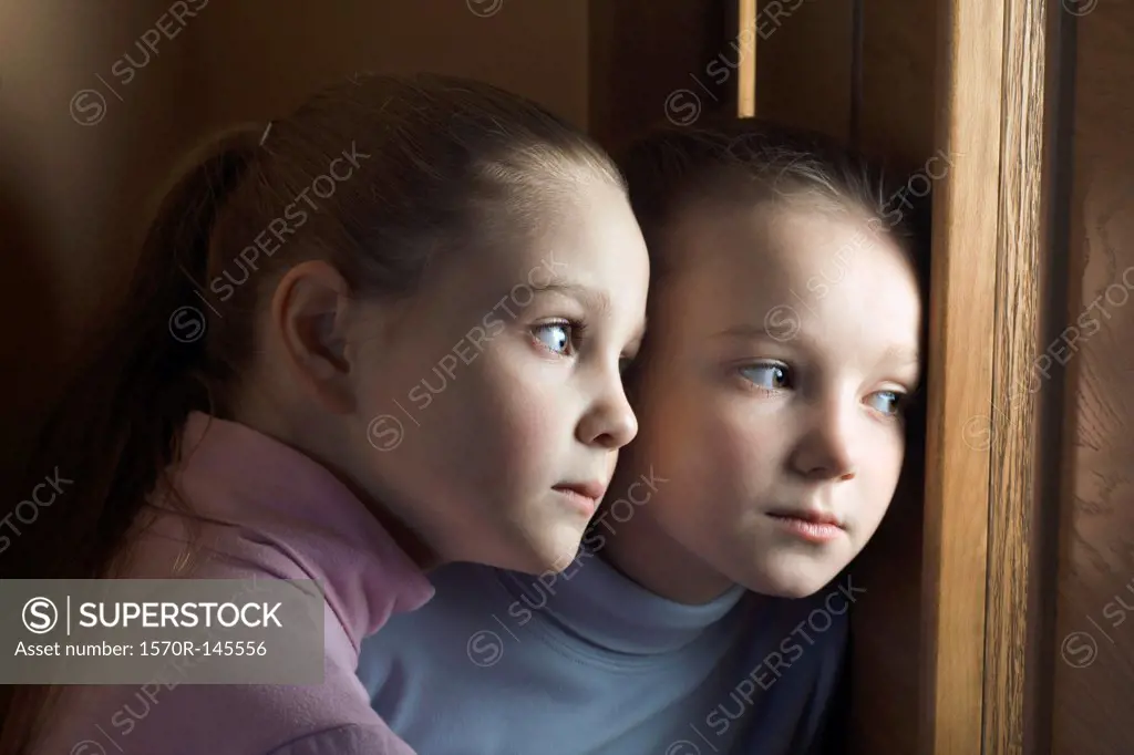 Two girls eavesdropping on door, close-up