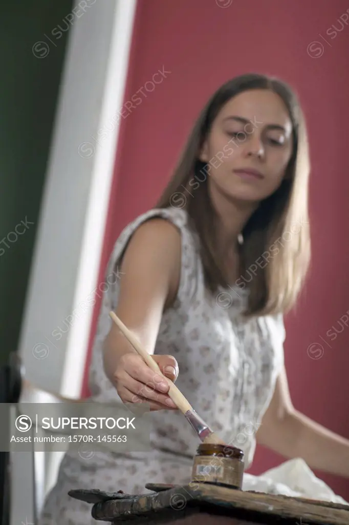 Young woman painting with paintbrush