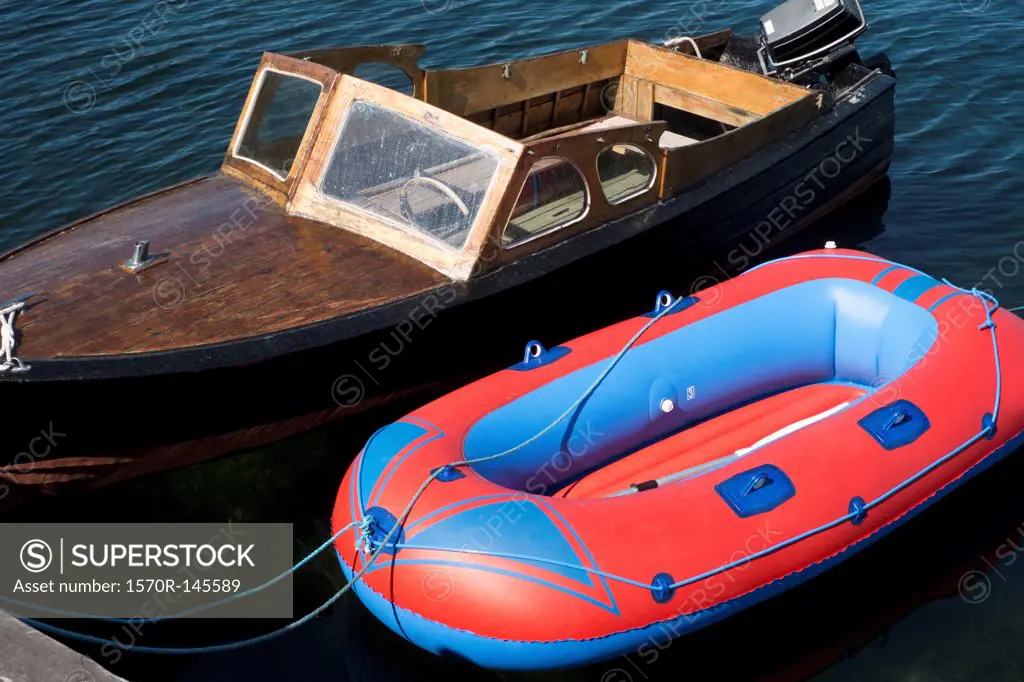 A retro motorboat moored next to a new inflatable boat
