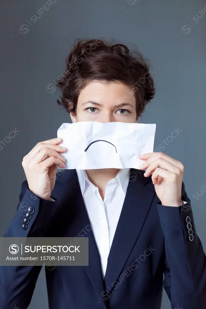 Portrait of mid adult woman holding paper with frown, close-up