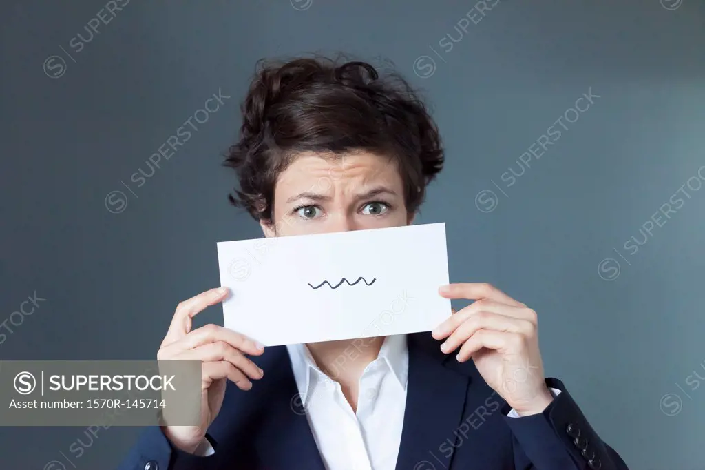 A worried looking woman holding paper with squiggle sign