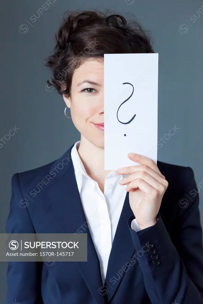 Smiling mid adult woman holding paper with question mark, close-up