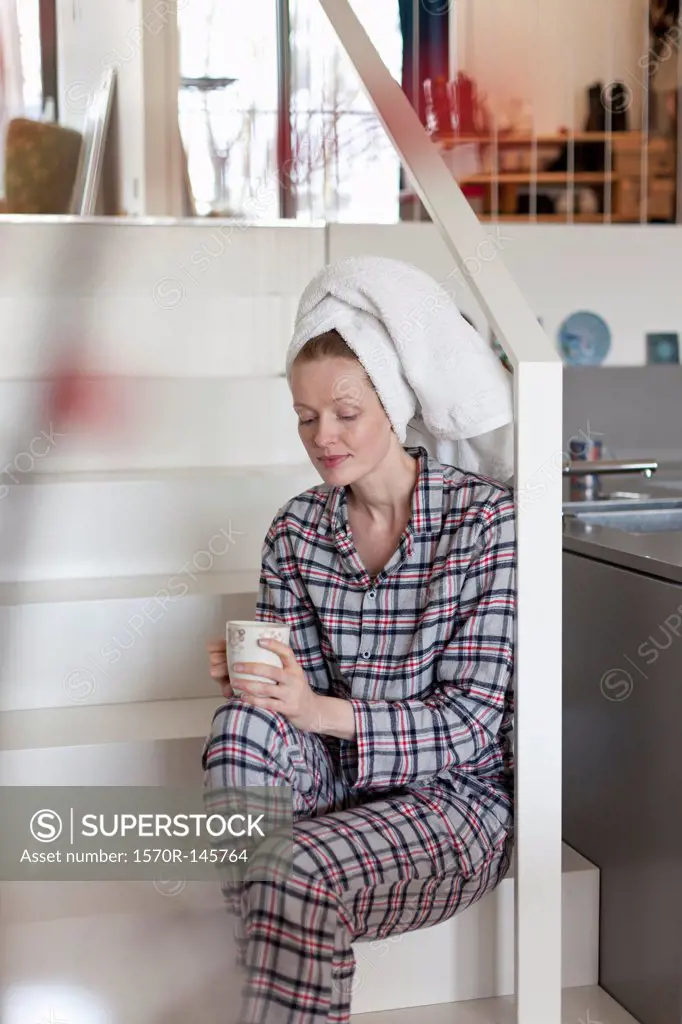 Woman holding coffee cup sitting on staircase