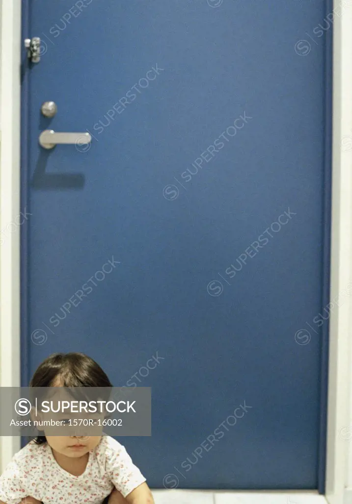 baby girl on floor in front of blue door