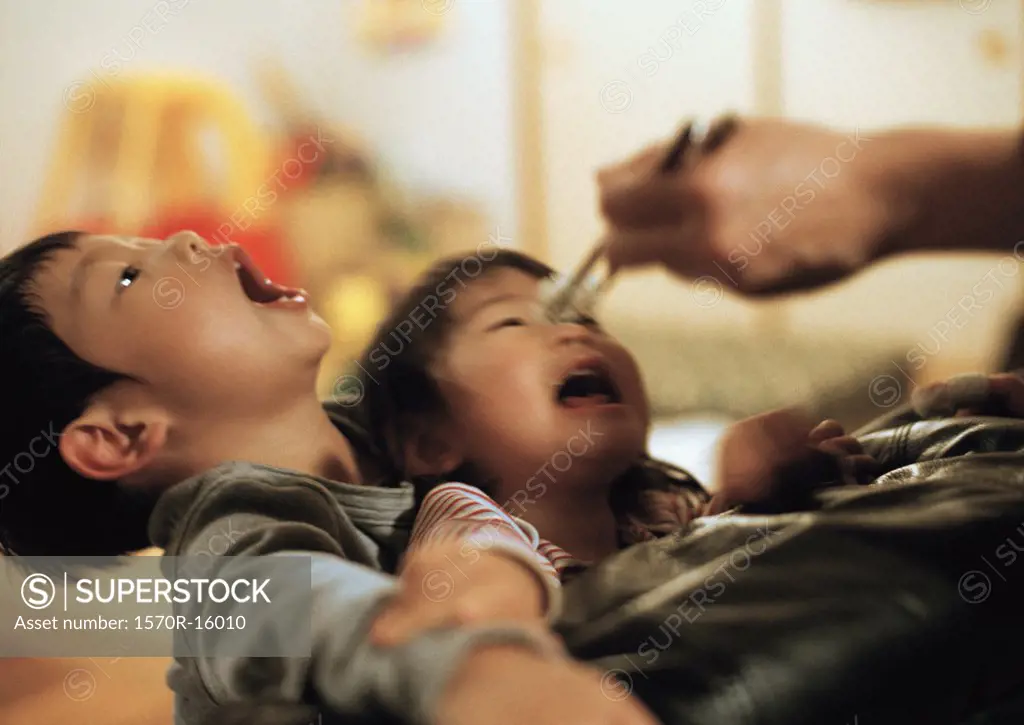 children with mouths open waiting for food from chopsticks