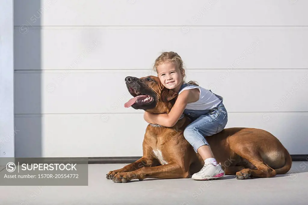 Portrait of cute girl sitting on dog outdoors
