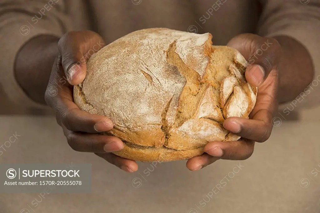 Midsection of man holding bread loaf at table