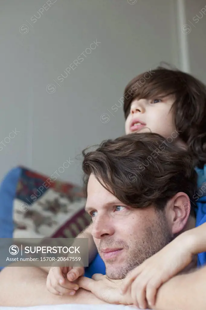 Son lying on father's back