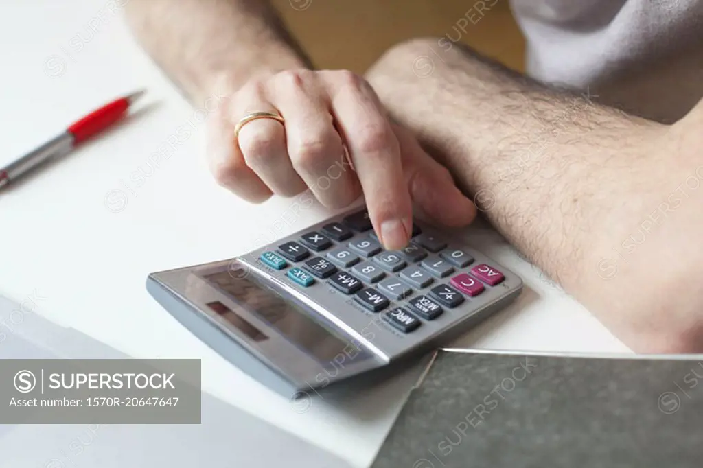 Cropped image of man using calculator at table