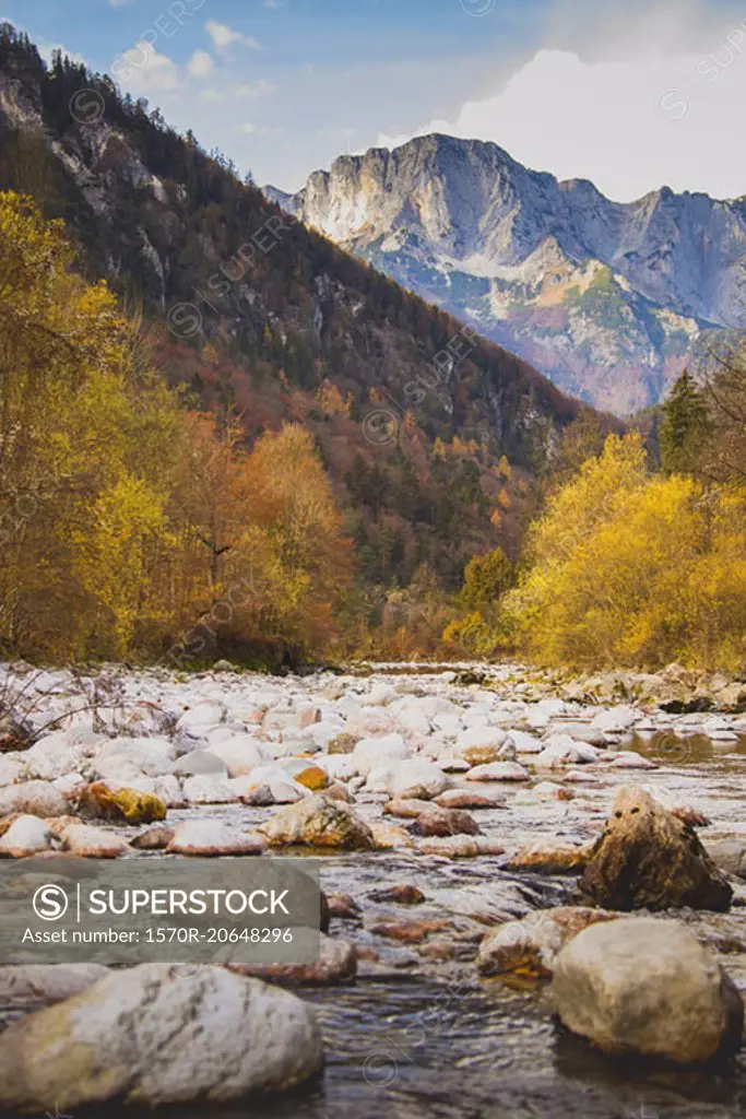 Stones at river against rocky mountains during autumn