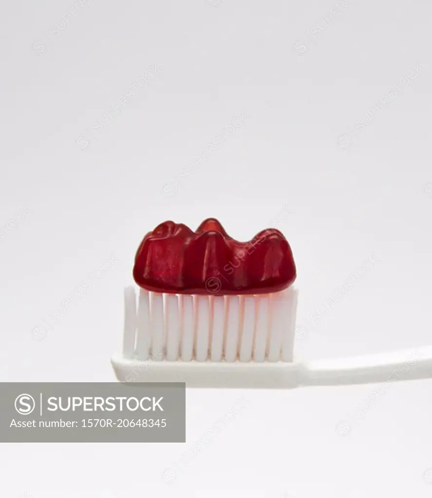 Close-up of gummy bear on toothbrush against white background