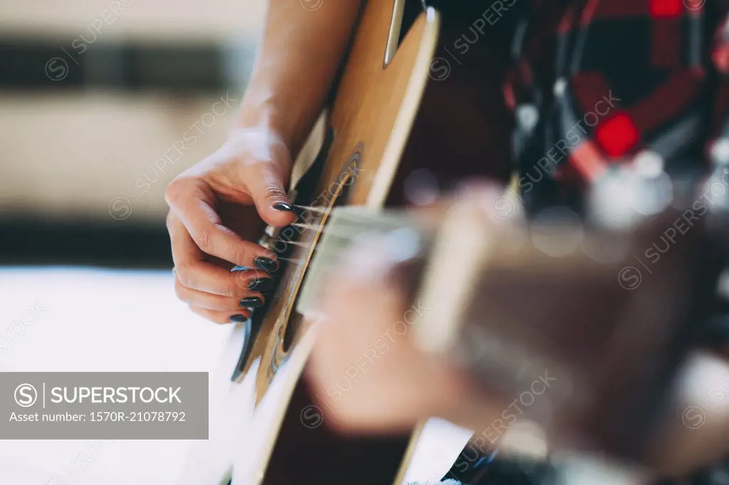 Cropped image of woman playing guitar at home