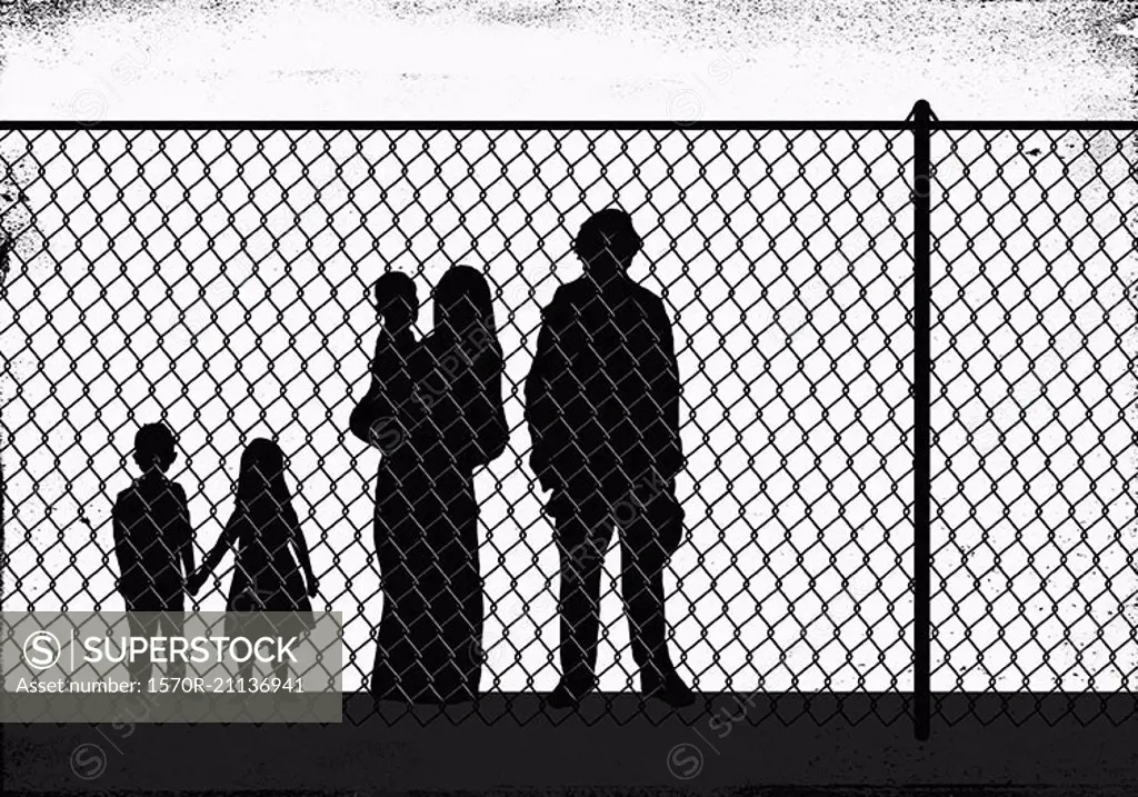 Silhouette family standing in front of fence