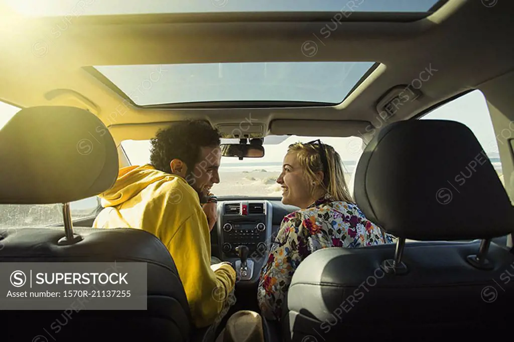 Rear view of happy couple looking at each other in car