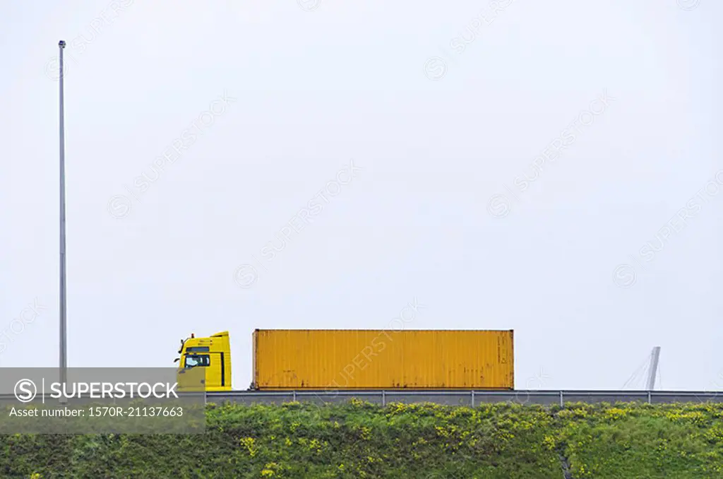 Yellow semi-truck on bridge against clear sky