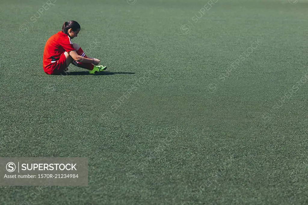 Side view of soccer player sitting on playing field