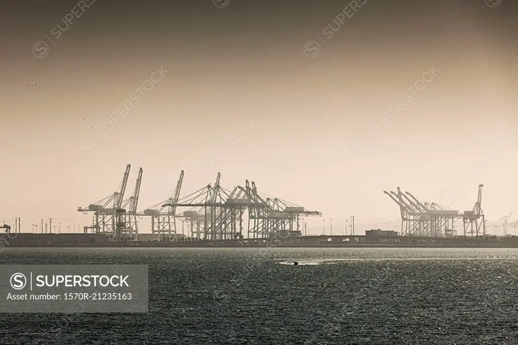 Sea in front of cranes at port against clear sky, Long Beach, California, USA