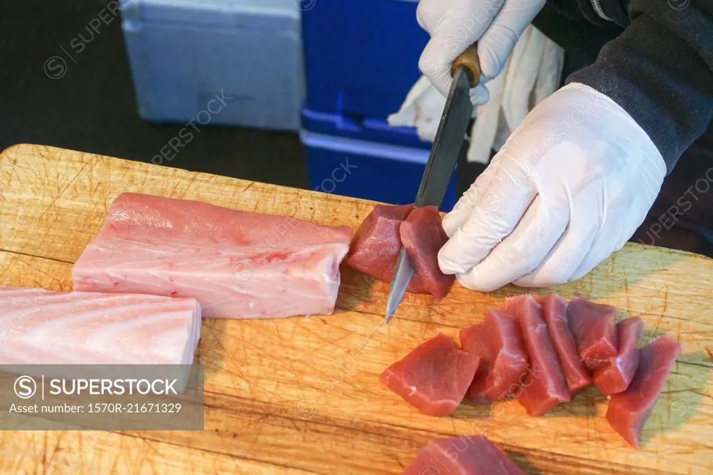High angle view of butcher cutting meat on board at shop, Tokyo, Japan