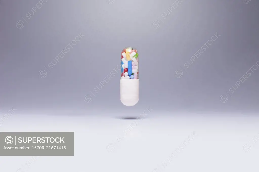 Capsule containing sprinkles in mid-air against gray background