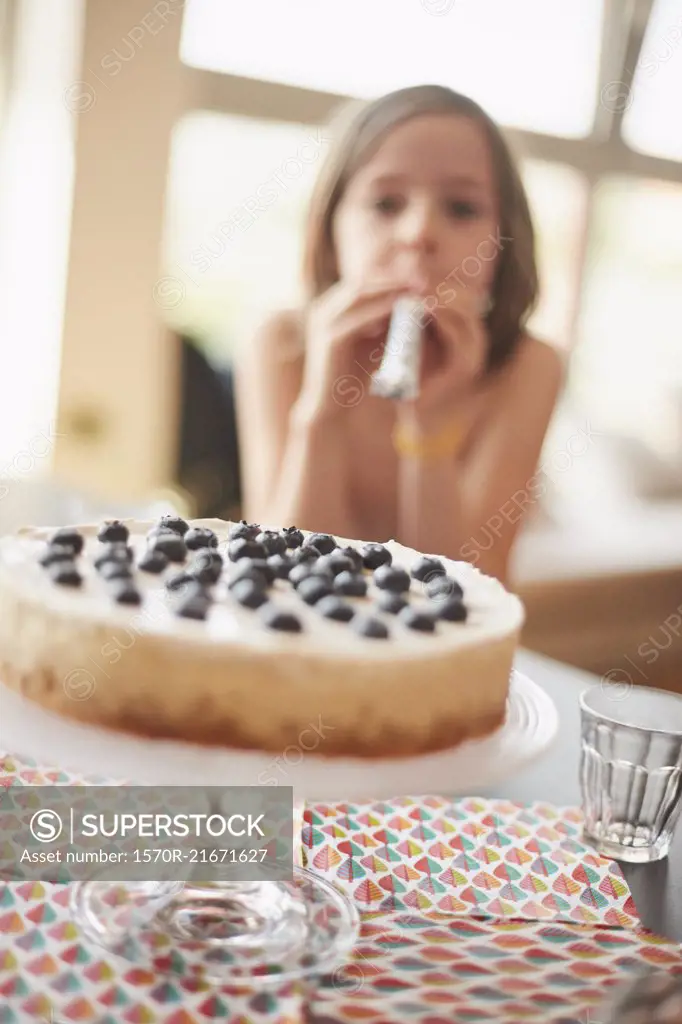 Cake on stand at table with girl in background