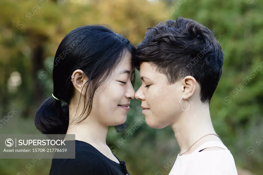 Close-up of smiling lesbian couple standing face to face at park