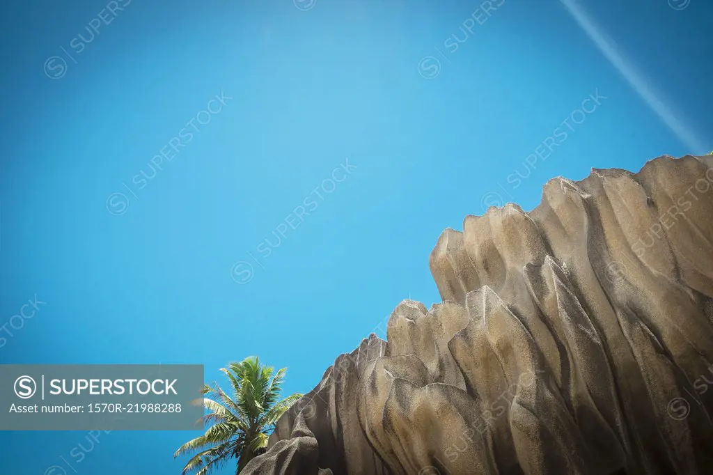 Low angle view of cliff against clear blue sky during sunny day