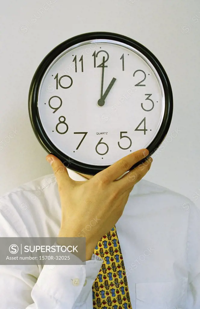 A businessman holding a clock in front of his face