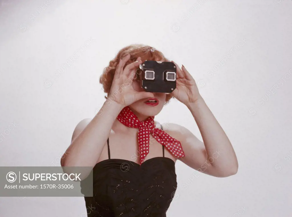 A 1950's woman with a red scarf looking through a slide viewer