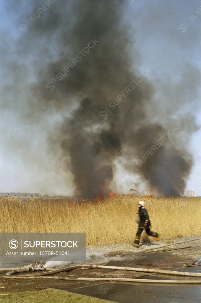 A firefighter running from a blazing field