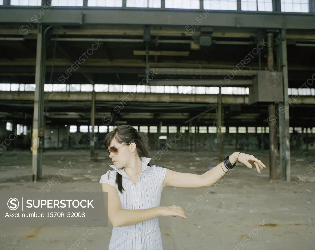 A woman dancing in front of an industrial construction site