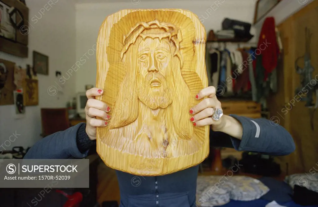 A young woman holding a carving of Jesus in front of her face