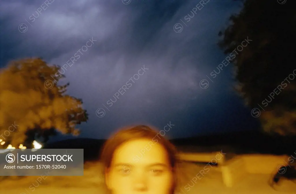 A young woman standing under stormclouds