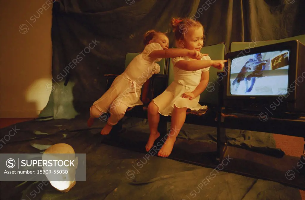 Two girls pointing to a television