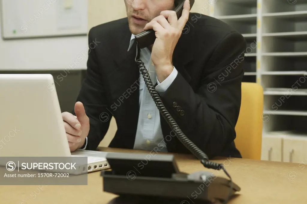 A man sitting at a desk talking on the telephone