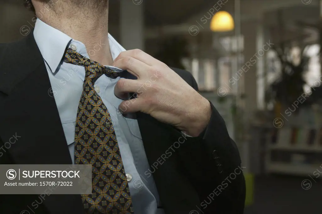 A man in a suit tugging at his collar