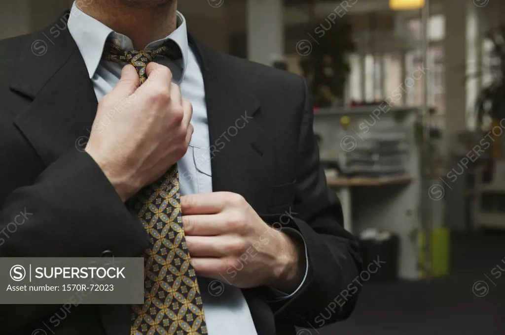 A man in a suit tugging straightening his necktie