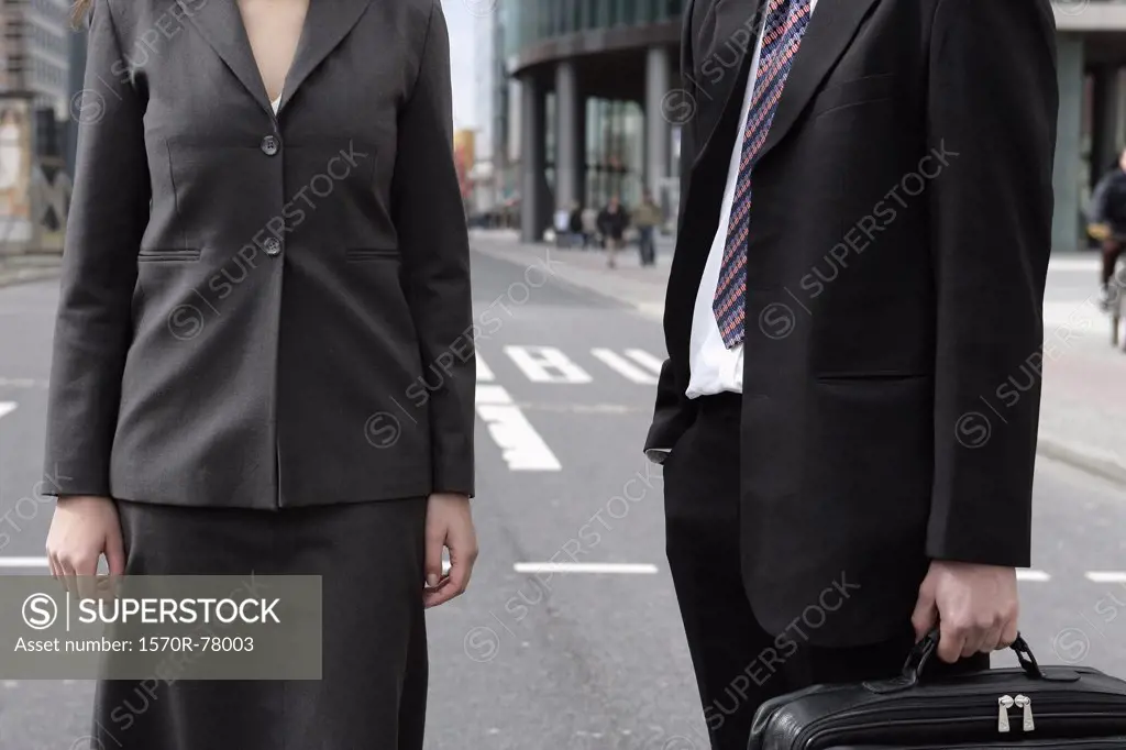 A businessman and a businesswoman standing in a city street
