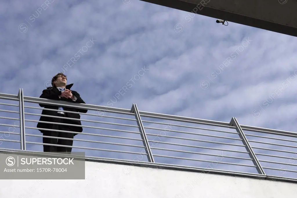 A businessman leaning on a railing 