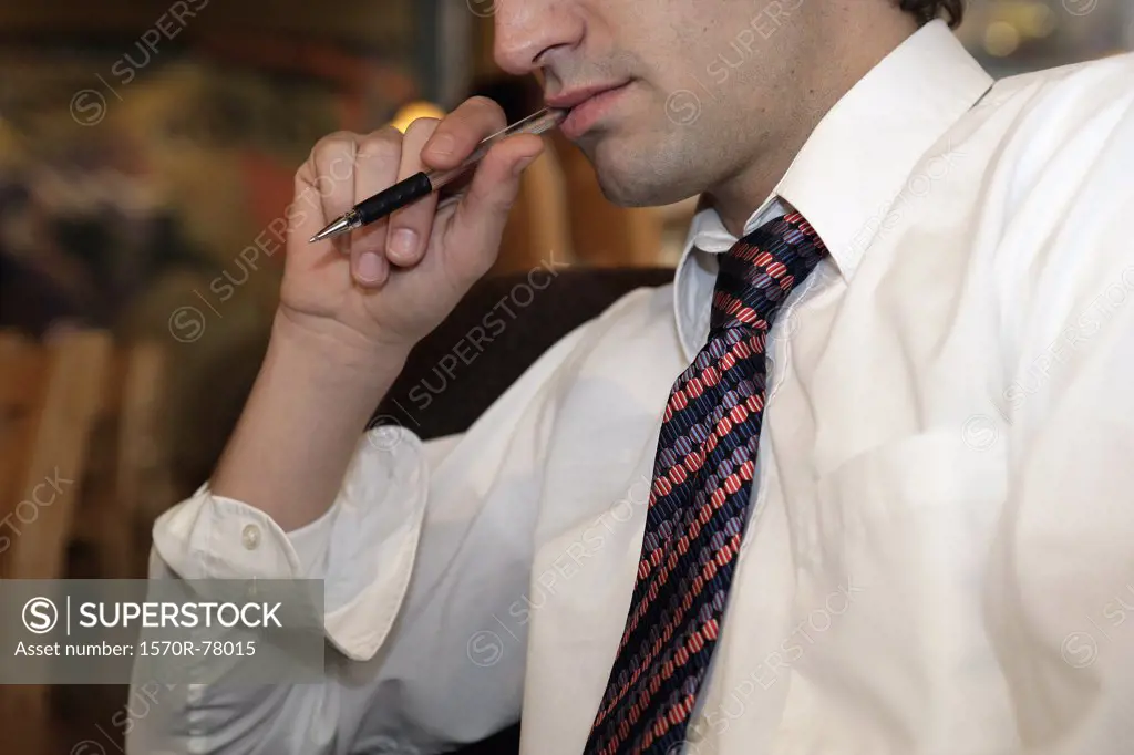 A businessman with a ballpoint pen in his mouth