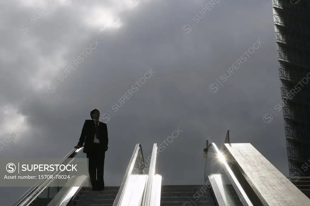 A businessman descending on an escalator