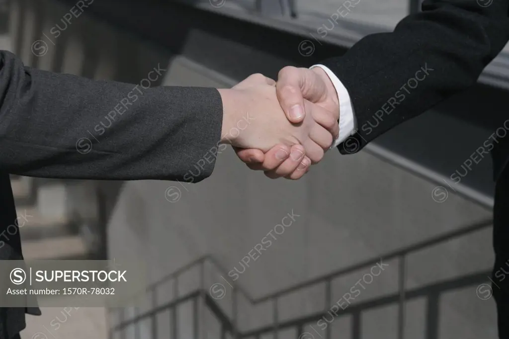 Two businesspeople shaking hands in a stairwell