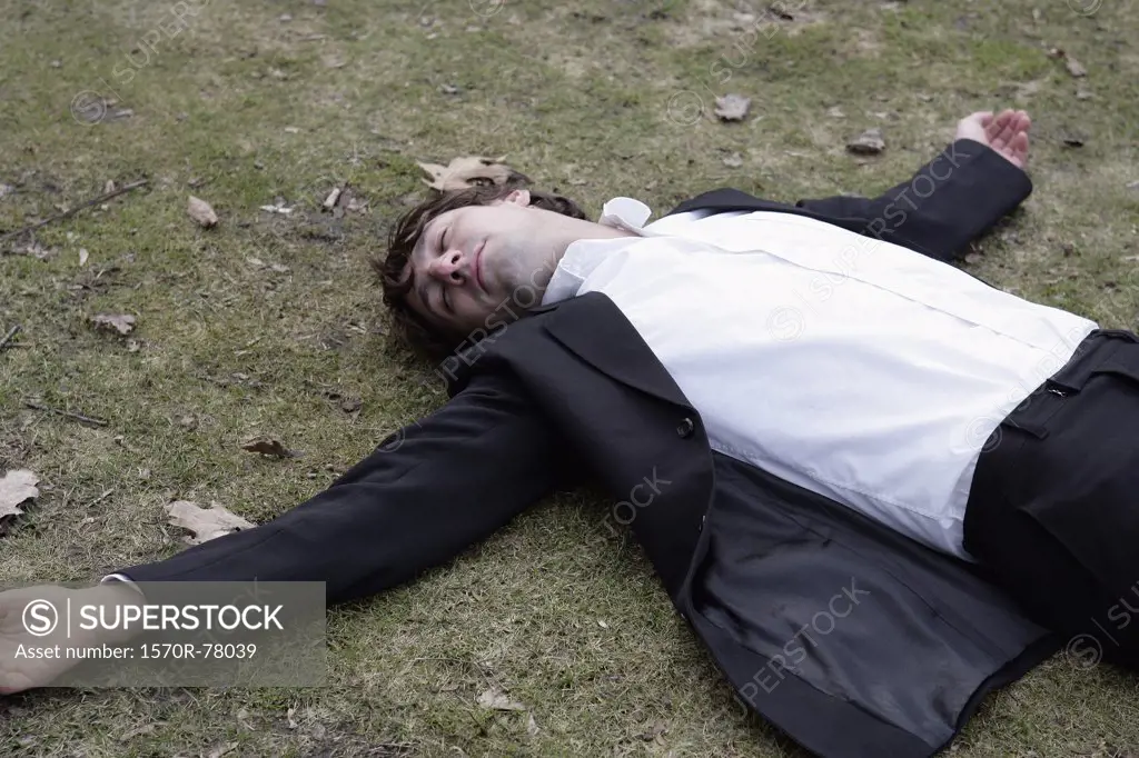 A businessman lying on his back in grass 