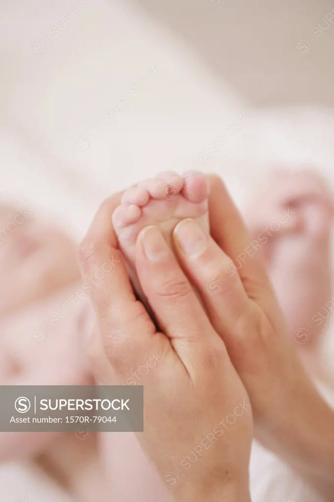 An adult massaging a baby's foot
