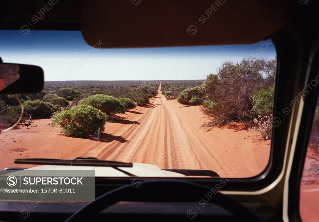 A view of a desert road in Australia through the windshield of an off-road vehicle