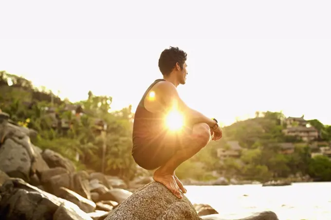 Serene young man crouching on ocean rock, Sayulita, Nayarit, Mexico
