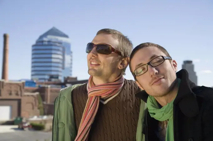 Two gay men smiling with cityscape behind