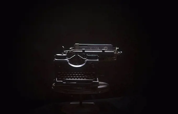 Typewriter on table against black background