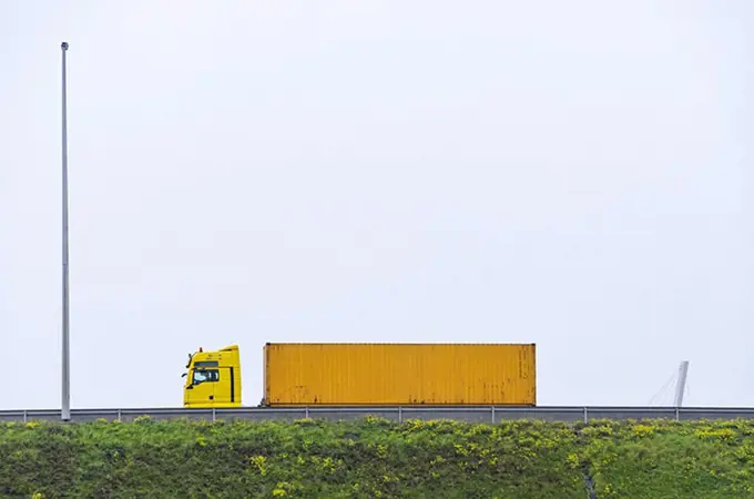 Yellow semi-truck on bridge against clear sky