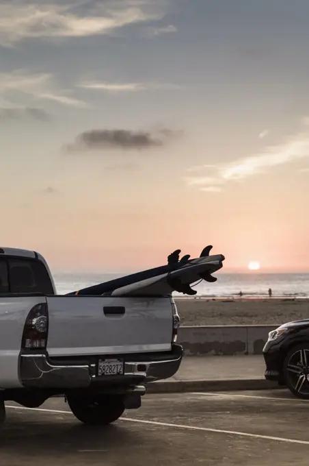 Surfboards in truck bed parked along beach at sunset, Newport Beach, California, USA