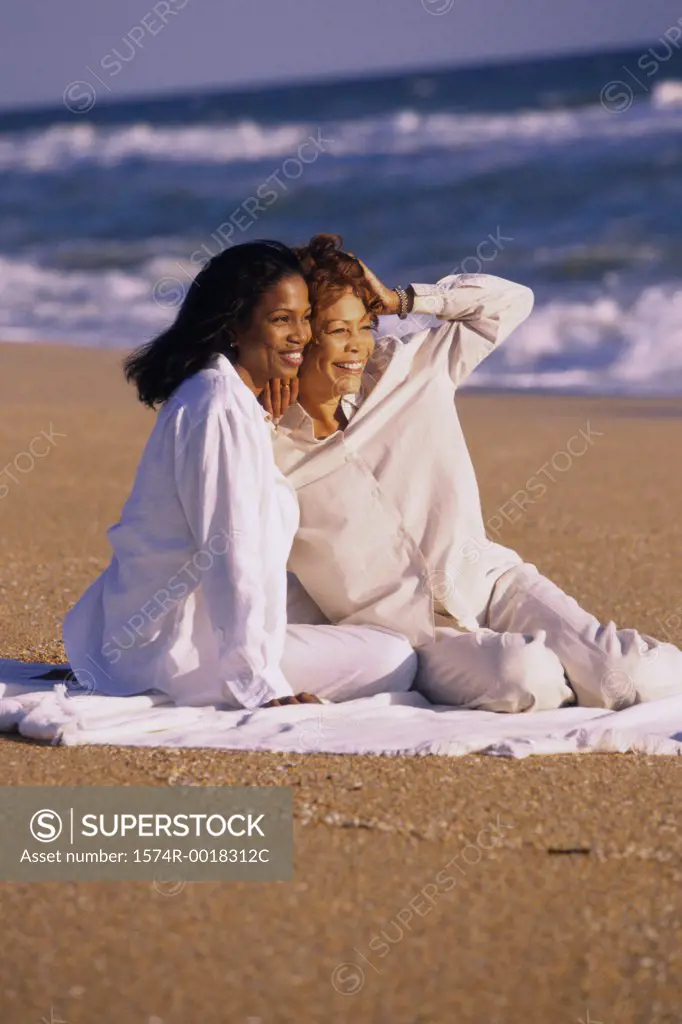 Mother and daughter sitting on the beach